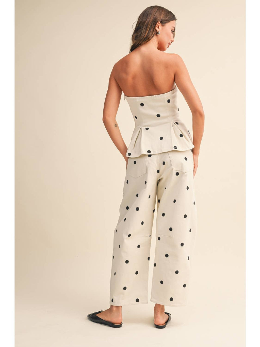 The woman is wearing a dressy two piece set that has a white base with black polka dots.